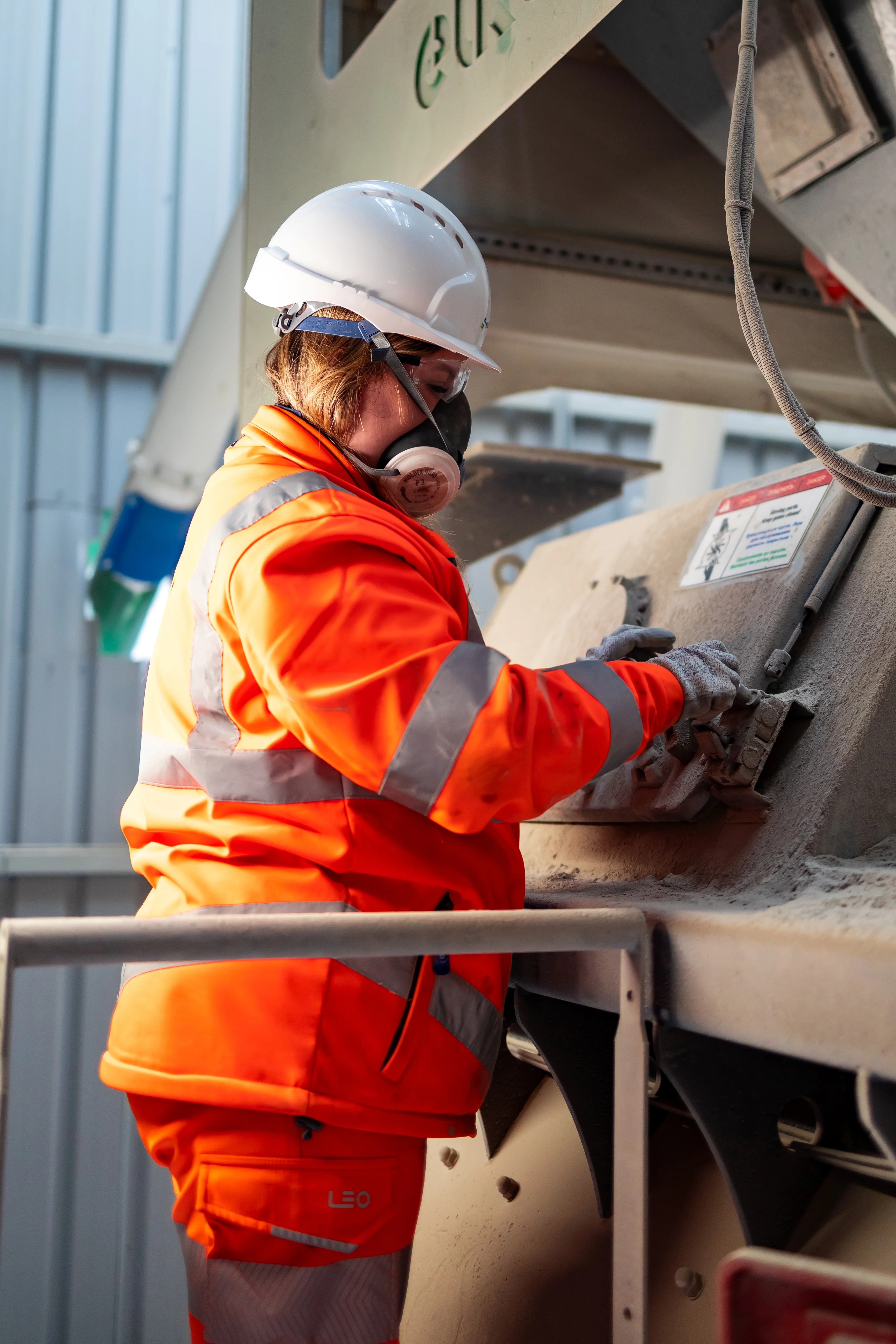 Emily Freeman in high viz PPE at Holcim Mortars at Holme Park working on machinery
