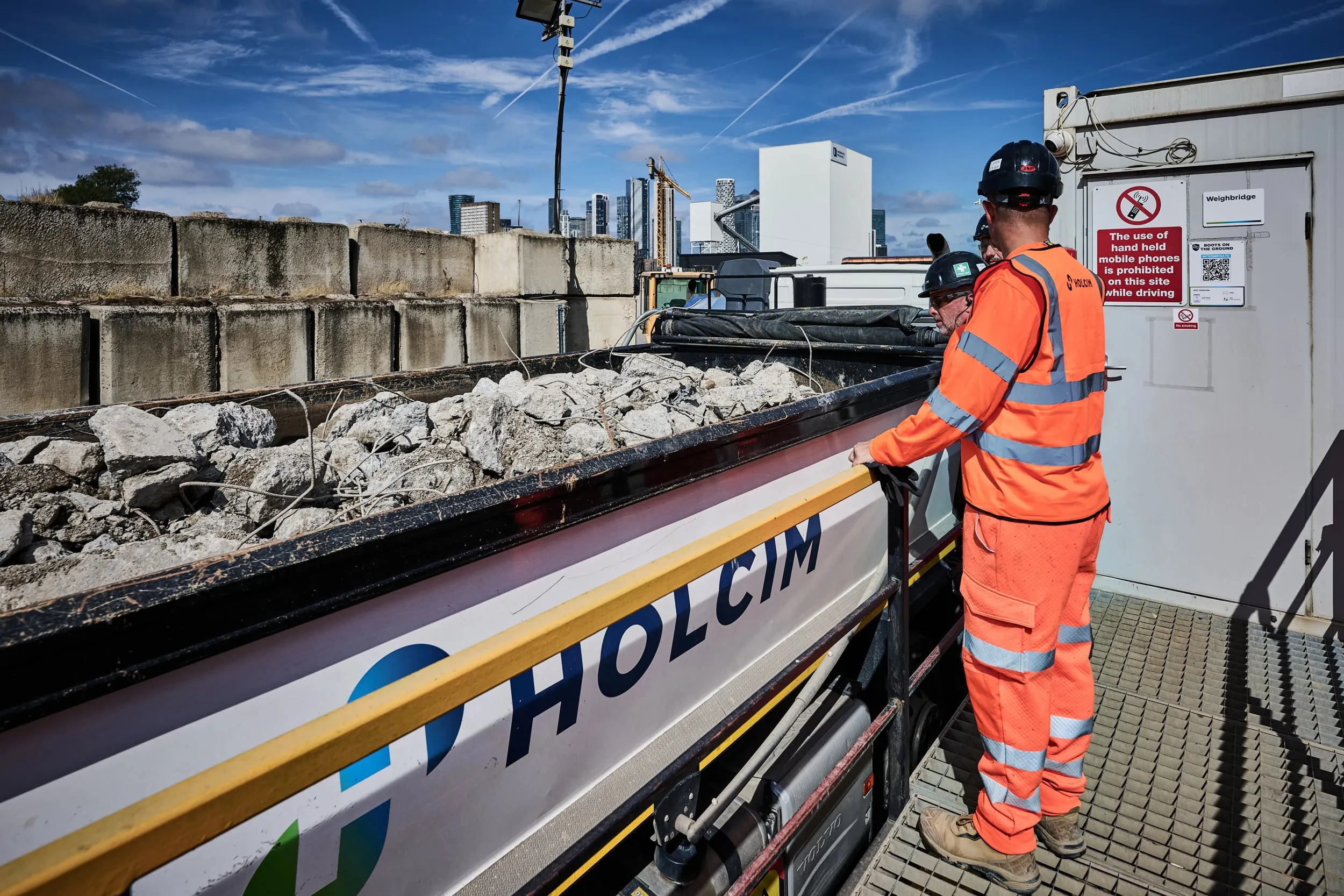 Holcim truck with CDM in the back with a PPE dressed worker inspecting