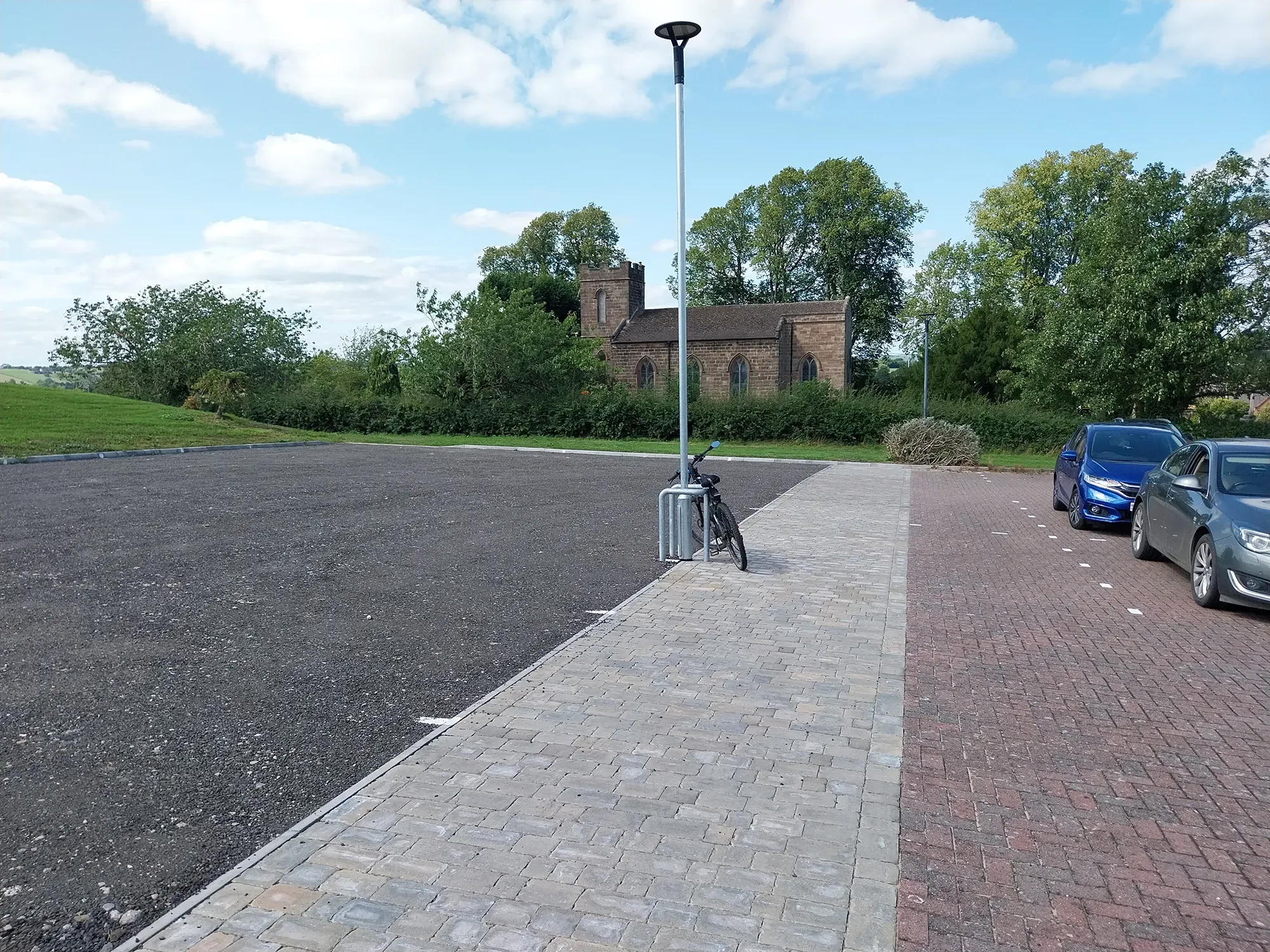 car park with lamp post, path and some cars to the right