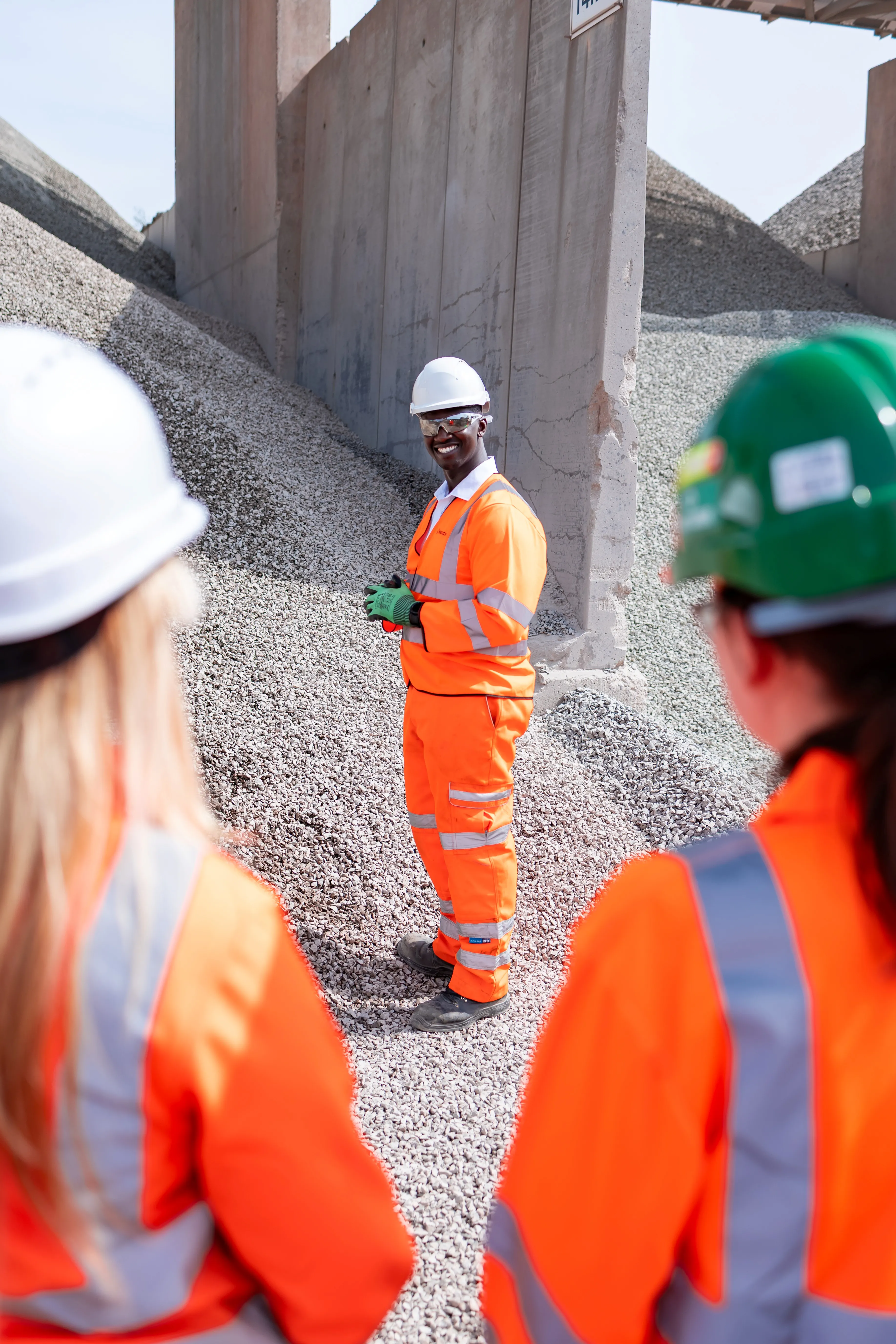Mustapha Nyass, regional operation manager, at the Sheffield Asphalt Plant in high viz. He is standing in front of a pile of aggregates.