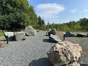 Gravel path with large boulders and signage in a wooded area