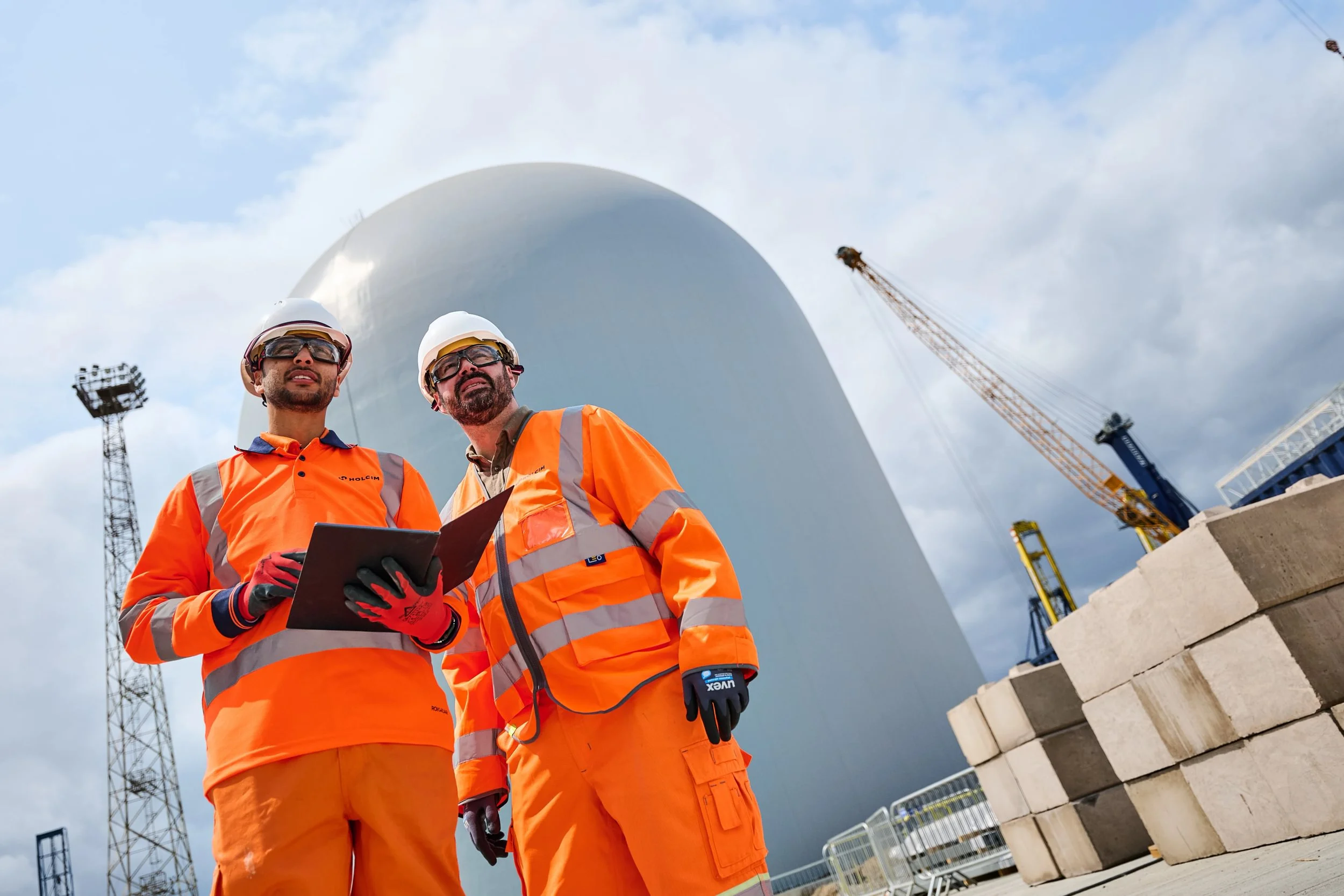 Two works wearing PPE holding a tablet at Holcim Tilbury Cement Terminal