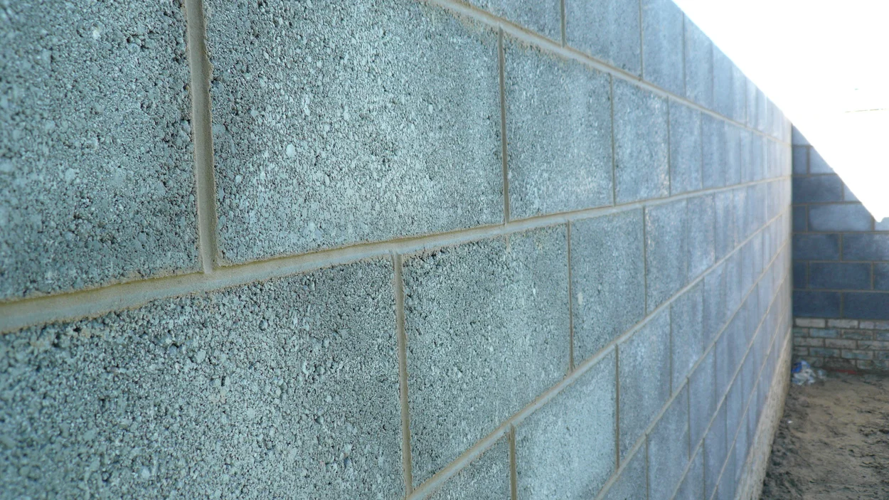 Close-up of a sturdy wall constructed from grey concrete blocks arranged in a neat running-bond pattern.