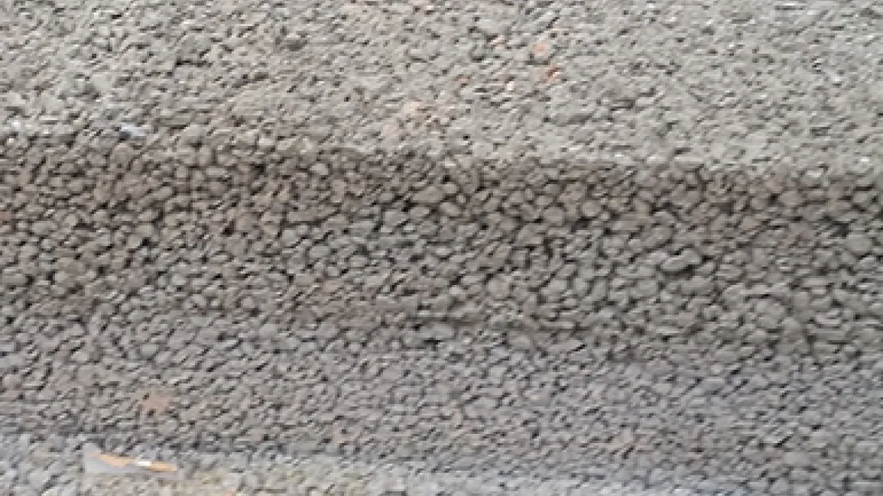 Cross-section of permeable concrete showing its porous structure with exposed aggregate and visible voids for water flow.