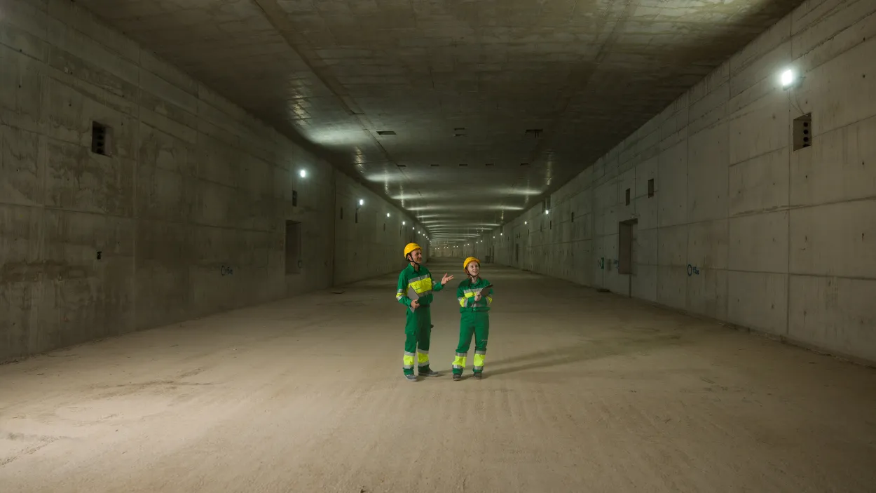 Two people in PPE standing in an empty tunnel