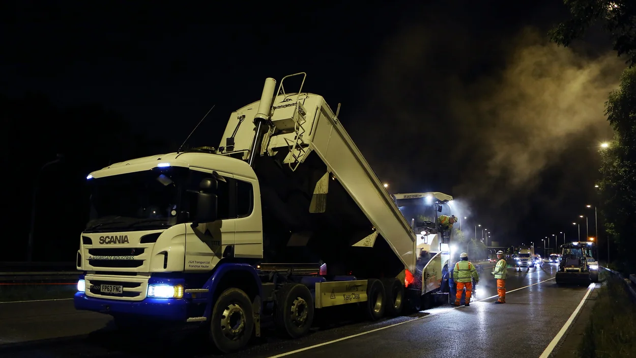 Lorries and a paver lined up on the M42 Motorway for night work