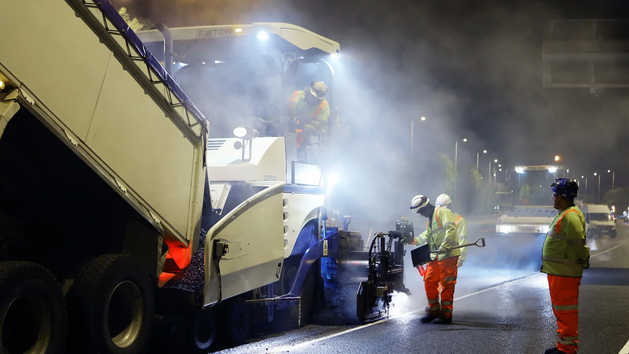 A lorry tips its load into a Holcim paver has it lays a new surface on the M42 motorway near Birmingham Airport