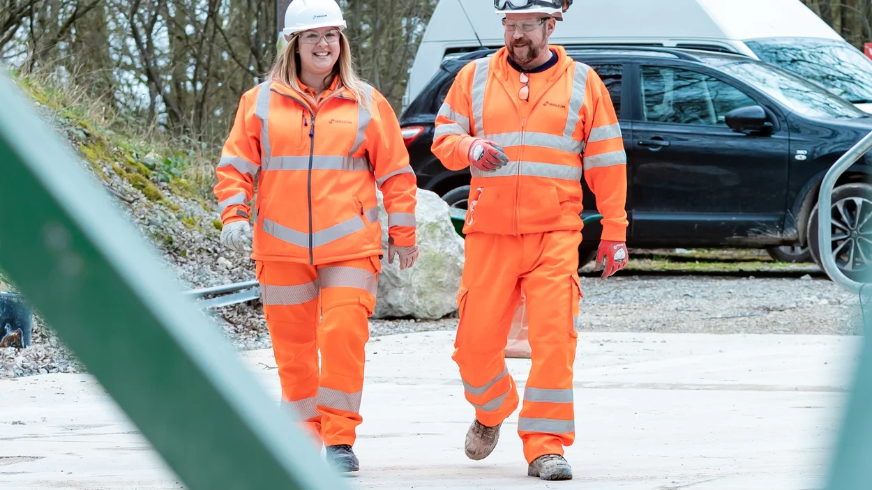 Emily Freeman in high viz PPE walking alongside a male colleague also in high viz PPEat Holcim Mortars at Holme Park