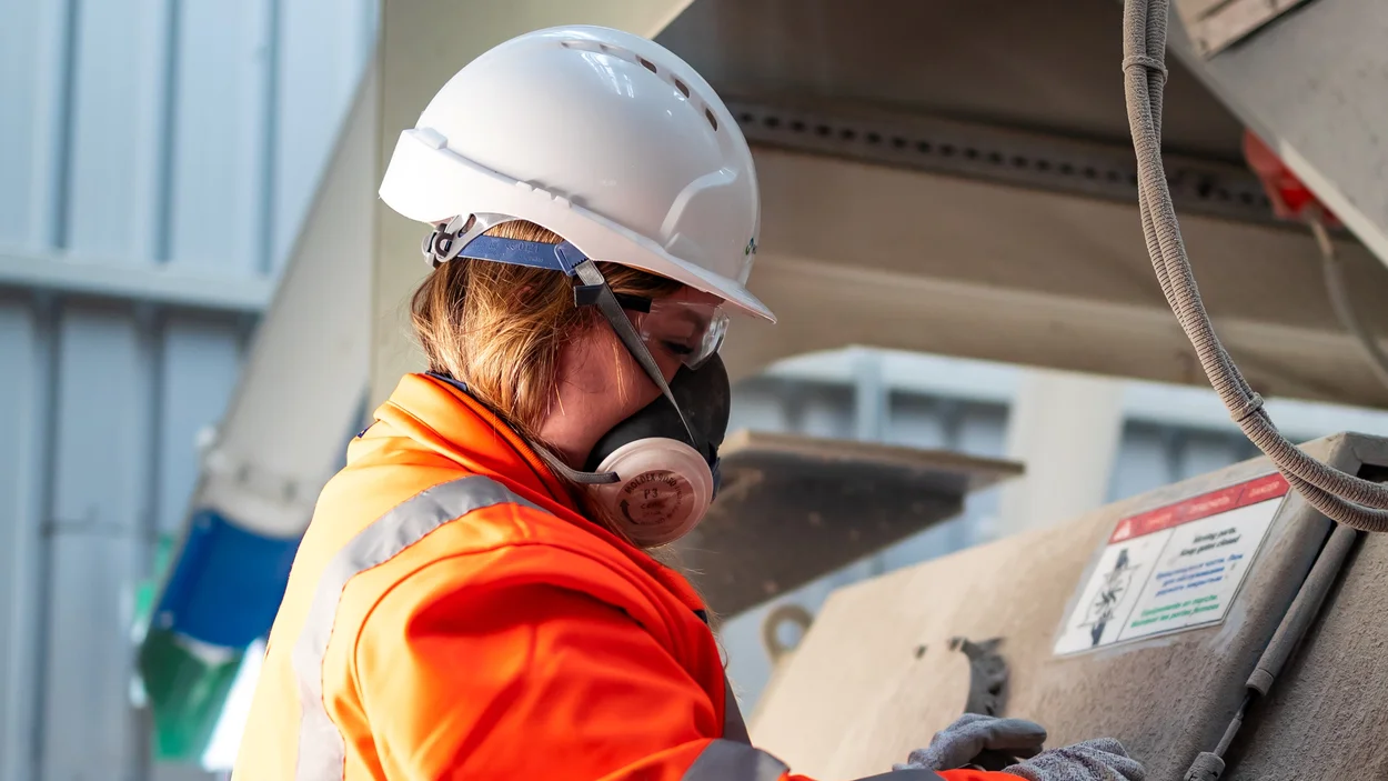 Emily Freeman in high viz PPE at Holcim Mortars at Holme Park working on machinery
