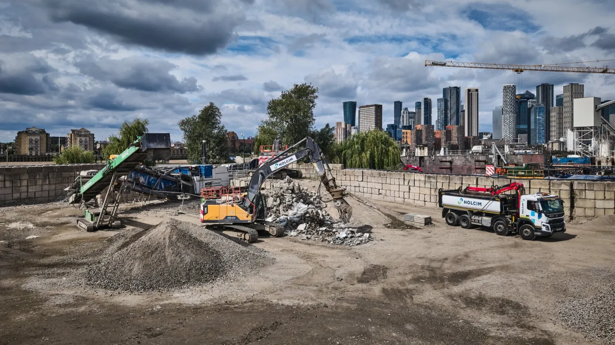 London skyline with Holcim branded excavator, conveyor and truck with aggregates