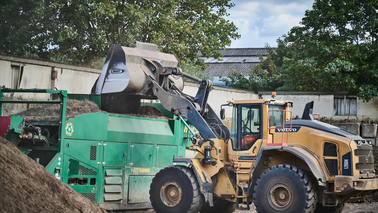 Soil transferring into a grading machine from a mechanical shovel