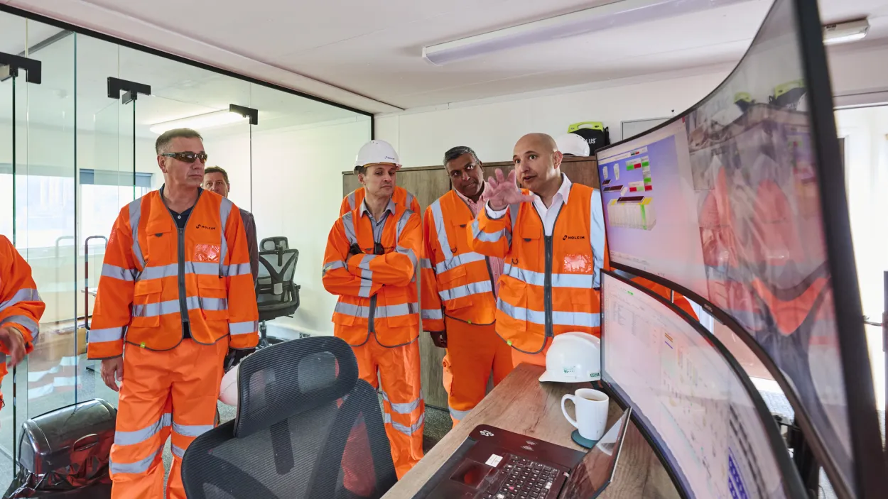 Adam Kutcher, right, demonstrates the control room at Holcim's London Bow plant