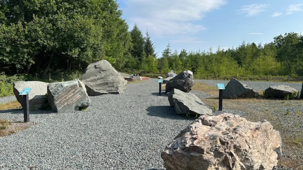 Gravel path with large boulders and signage in a wooded area