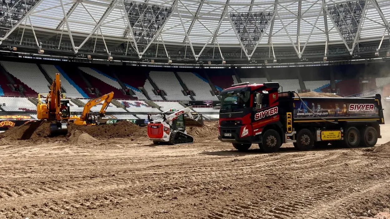 Excavators and trucks moving dirt in London Stadium