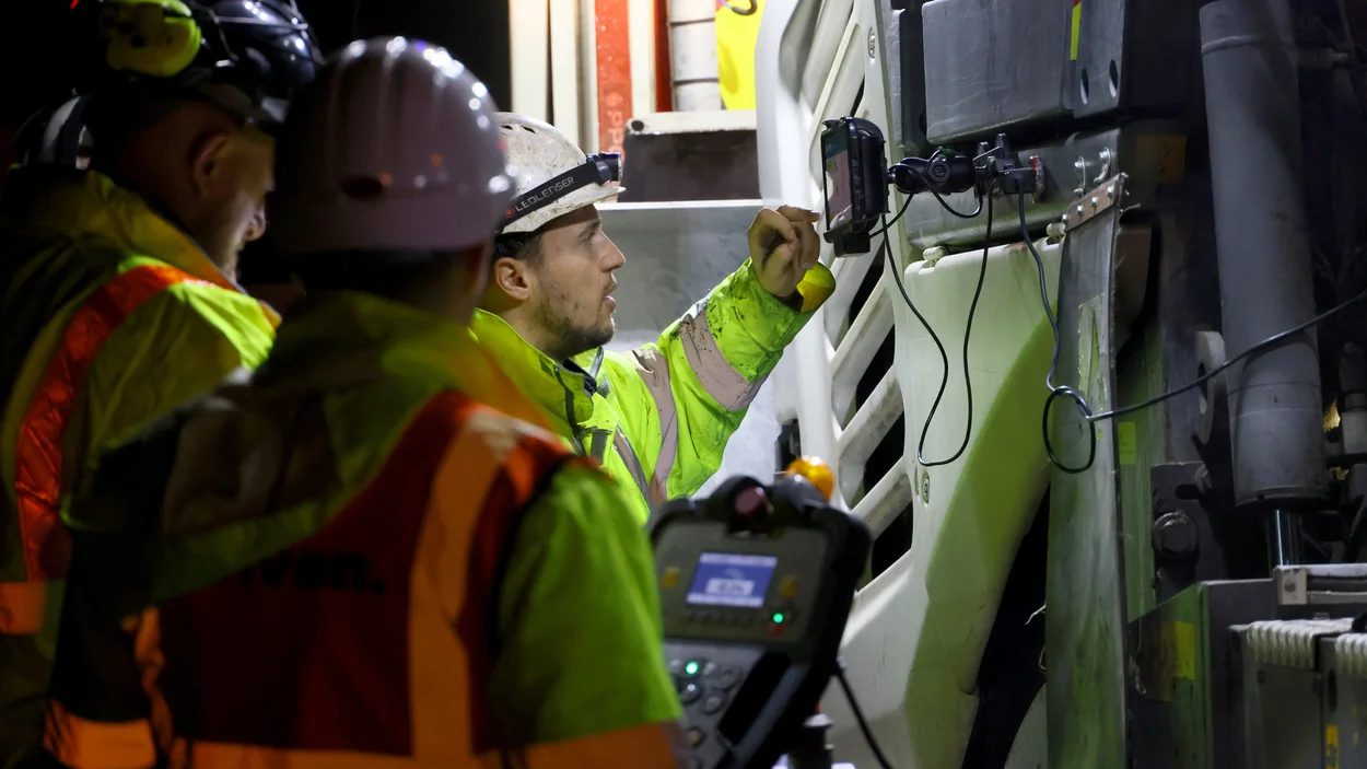 Workers in high viz key data into of of the pieces of machinery being used to resurface the M5 motorway