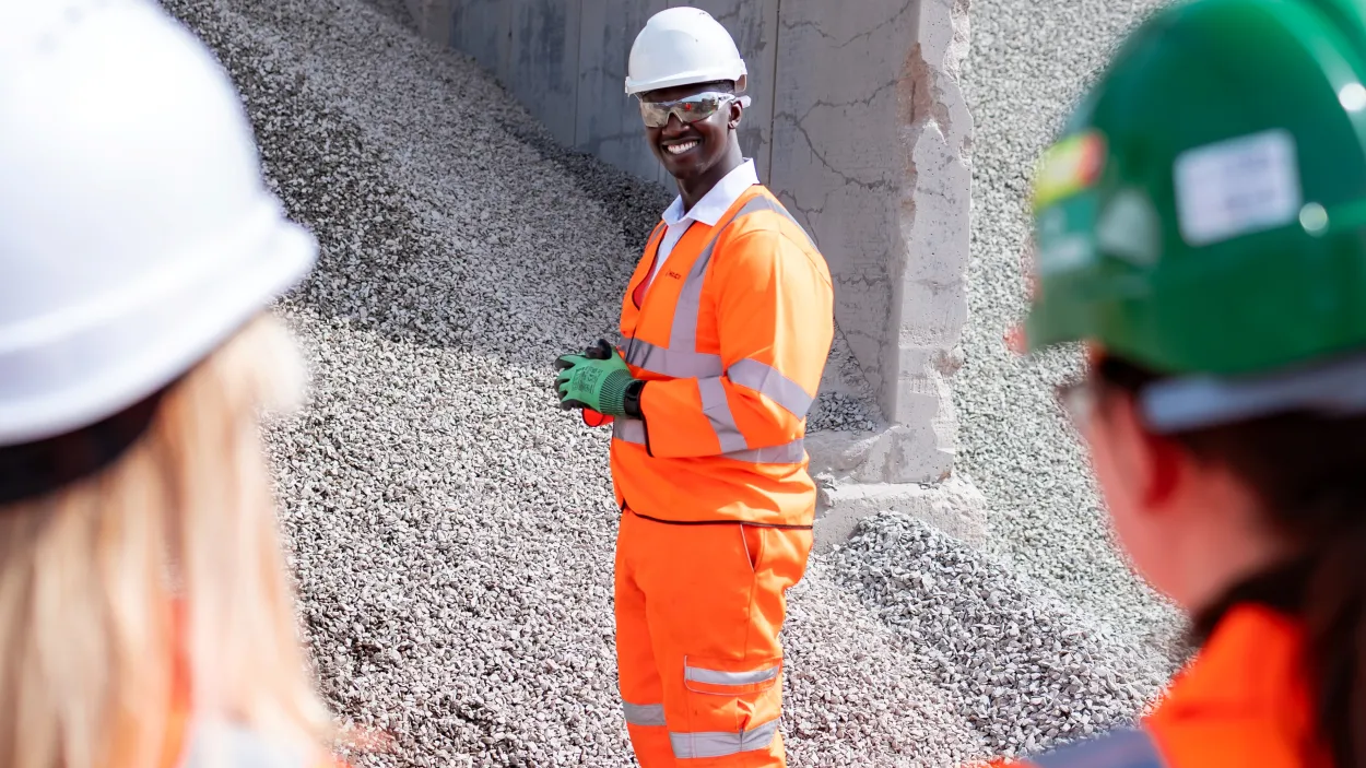 Mustapha Nyass, regional operation manager, at the Sheffield Asphalt Plant in high viz. He is standing in front of a pile of aggregates.