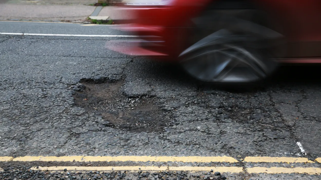 Road with a car driving over a pothole at speed