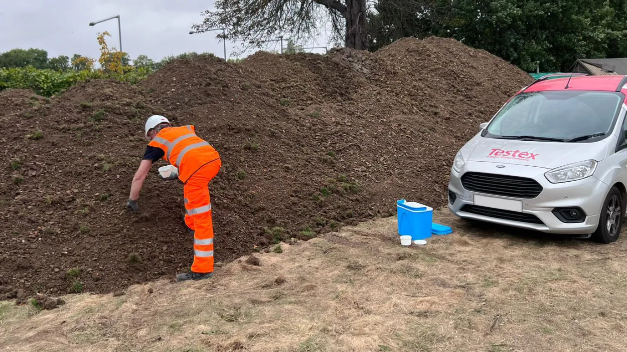 PPE worker inspecting soil next to a Testex car