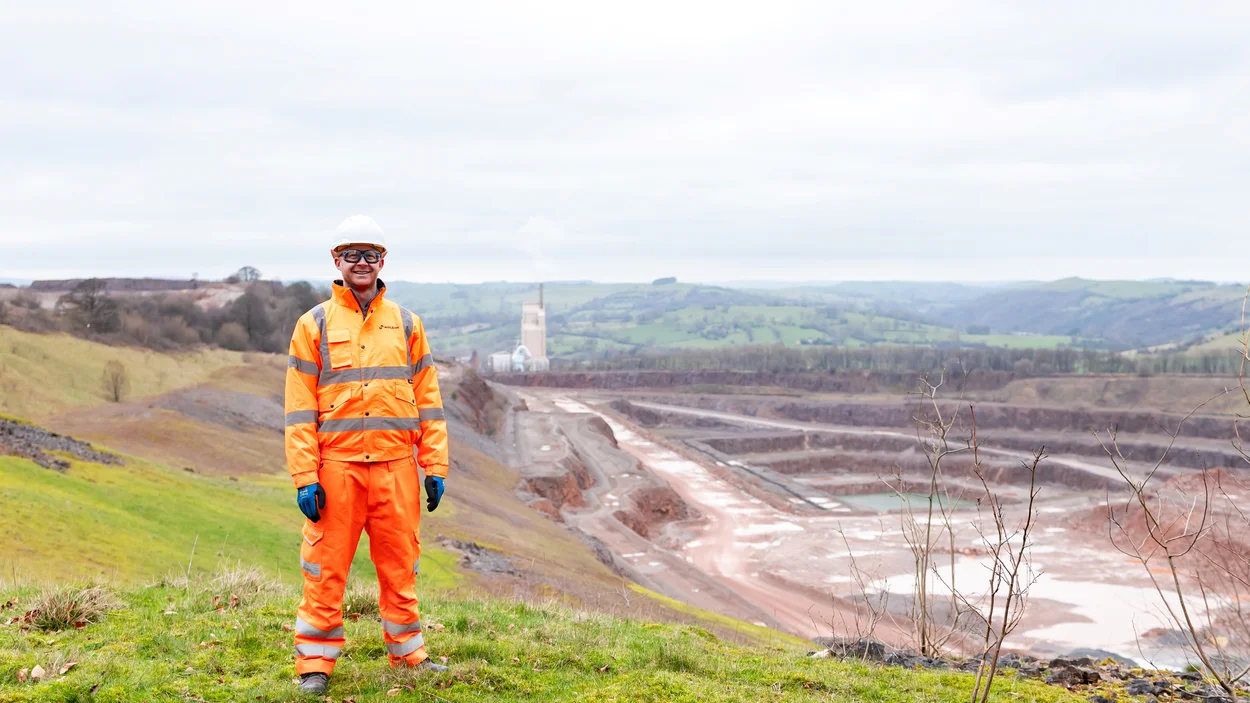 Head of Sustainability for HOlcim UK, Tom Redfern in high viz PPE with Cauldon Quarry and cement plant in the background