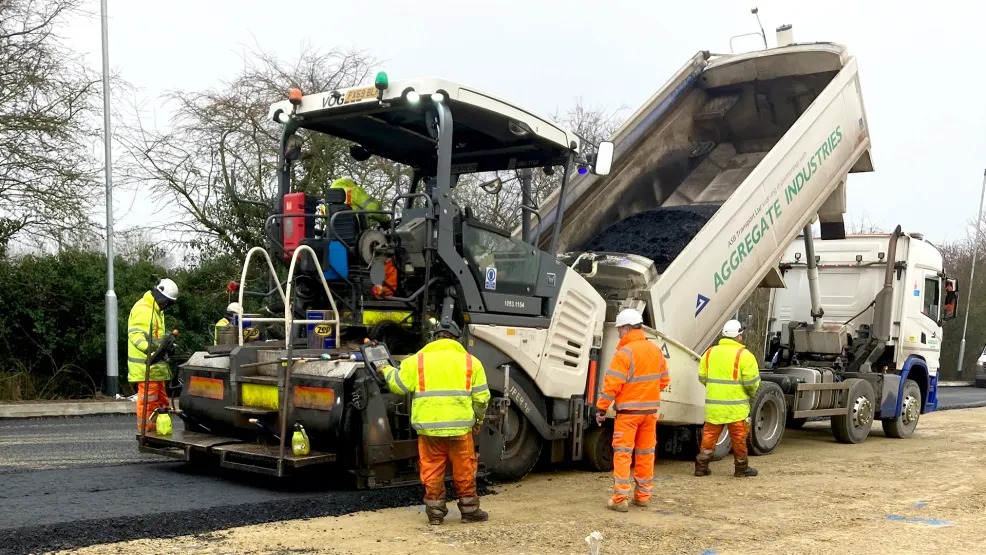Tipper pouring fresh asphalt into a paver