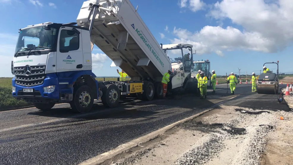 Tipper truck pouring asphalt into a paver on the A30 Carriageway