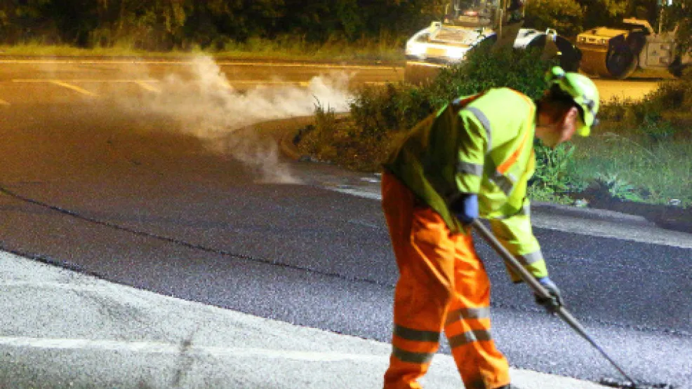 Worker levelling asphalt on the M1 smart motorway scheme at night