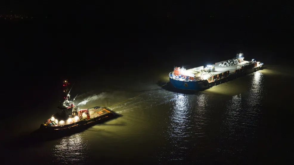 Tug boat moving the SeaRock barge around the Blue Anchor coastline at night