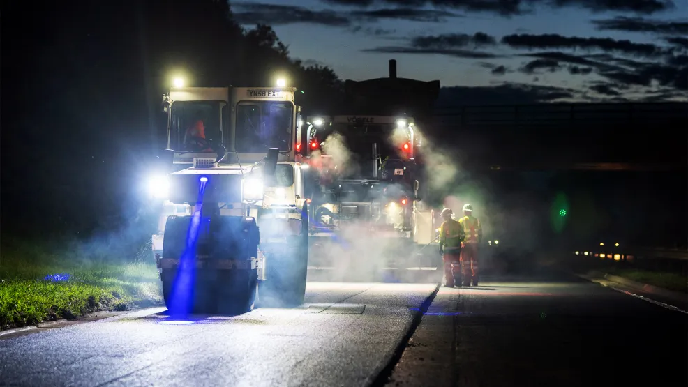 Roller flattening fresh asphalt with blue lights on A90