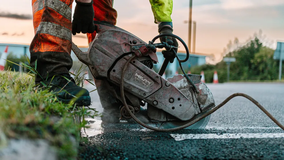 Worker cutting out a section of asphalt with a circular saw
