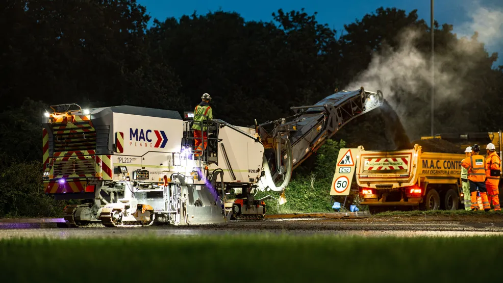 Planer and workers removing old asphalt and depositing planings into an aggregate industries truck