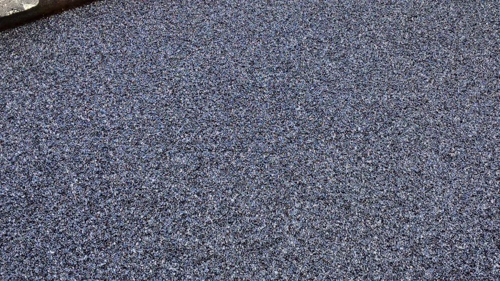 Fresh asphalt being laid alongside tramlines with a worker