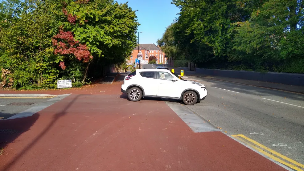 A car pulling out of a petrol station over a cycle kerb demonstrating it's use