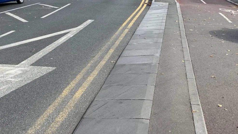 A busy road with a cycle lane edged with cycle kerbs