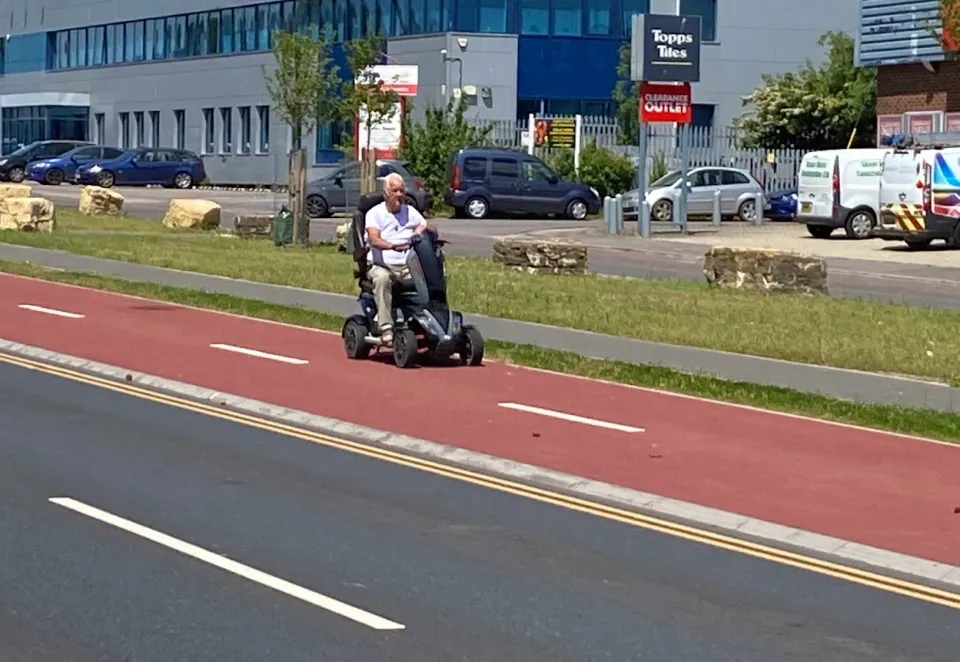 man on mobility scooter on red cycle path