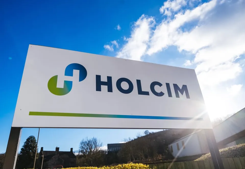 Sign that reads "Holcim" with the sun and clouds in the background