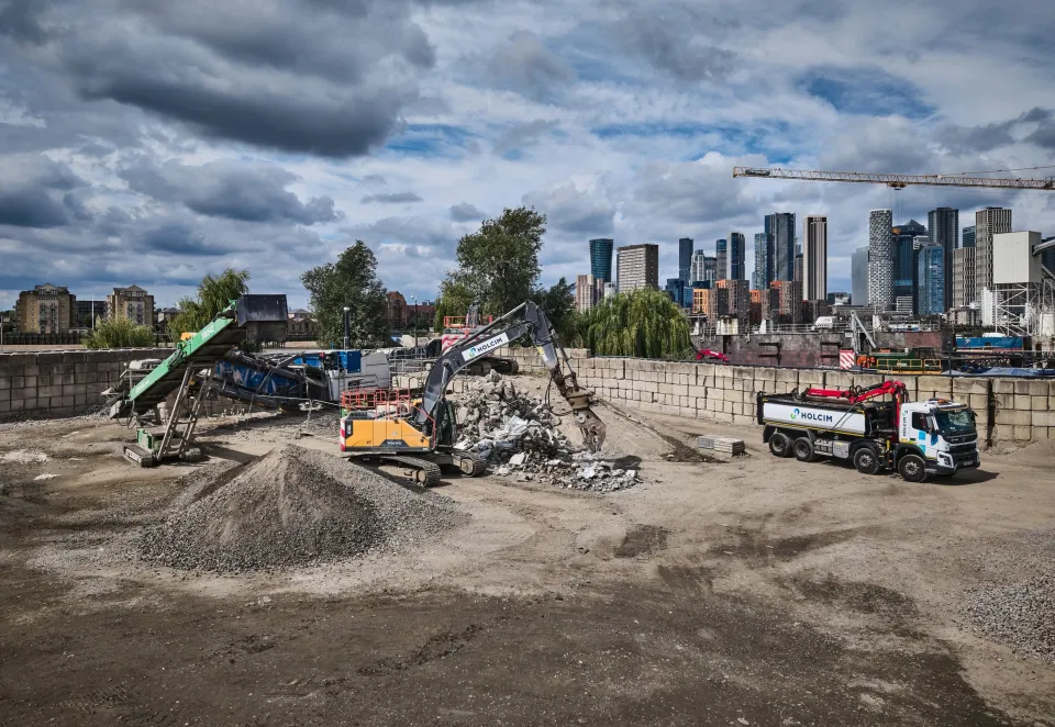 London skyline with Holcim branded excavator, conveyor and truck with aggregates