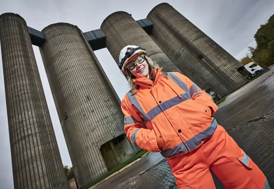 Lady in PPE standing in front of cement silos