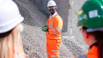 Mustapha Nyass, regional operation manager, at the Sheffield Asphalt Plant in high viz. He is standing in front of a pile of aggregates.