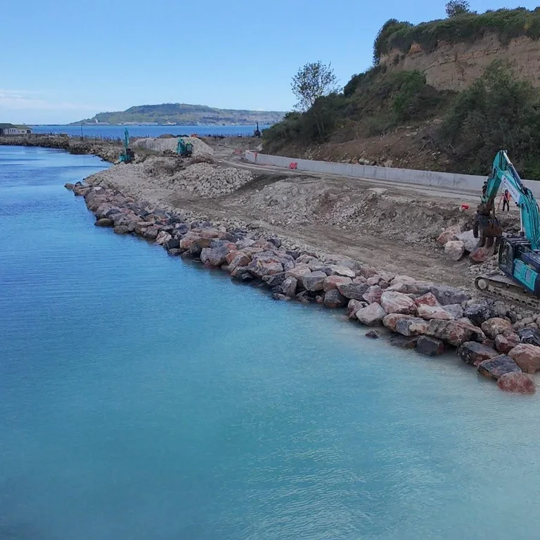Limestone rock armour boulder from Holcim's Torr Quarry being put into new sea defences at Newtons Cove in Weymouth