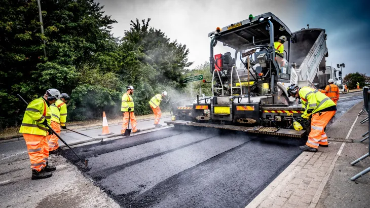 Aggregate Industries workers resurfacing a road with tools and machinery.