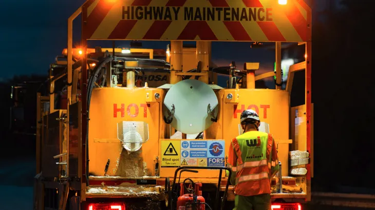 Worker standing next to a highways maintenance truck