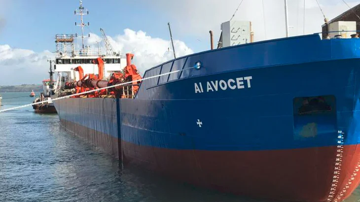 Large blue aggregates ship at a dock with the name AI Avocet on the side