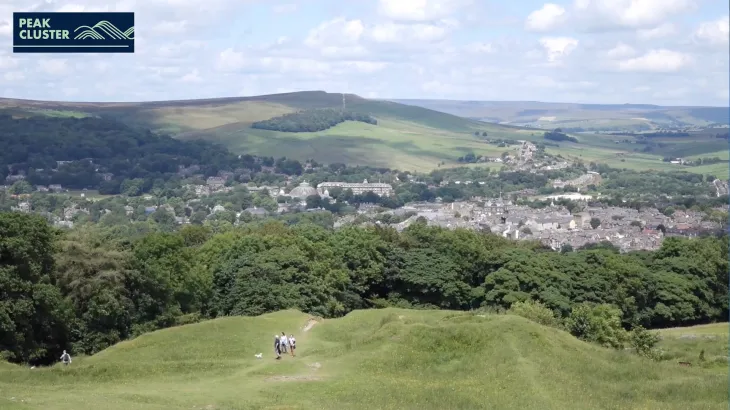 peak cluster logo in top left with a vista of rolling hills, a small town and blue skys