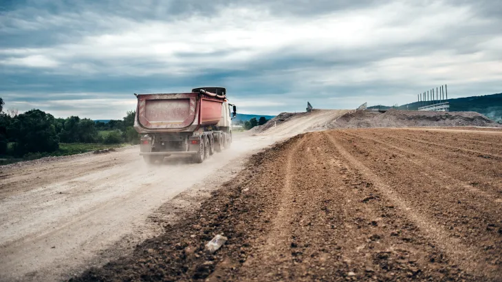 Truck driving down a dusty road