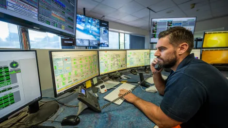Man on phone in front of supply chain and logistics computer screens