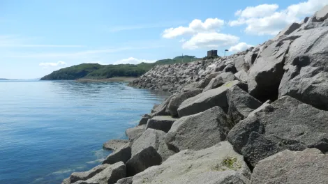Armourstone on a coastline with a castle in the background