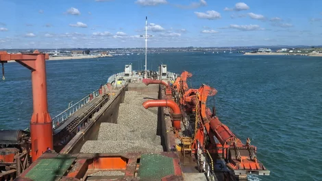 Large aggregates ship approaching a marina area near land