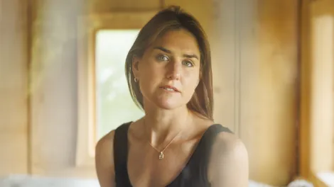 Lady wearing a black vest in a yellow stained room