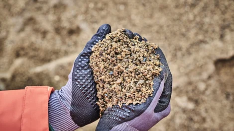 A close up of sand in a worker's gloved hand at Holcim's Grovebury Specialist Sands Quarry, 