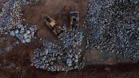 An aerial view of an excavator loading a dumper truck with materials at Bardon Hill Quarry
